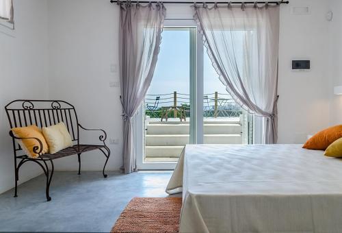 a bedroom with a bed and a chair and a window at Villa Torre Dell'Altomare con piscina, blocco n2 - Apulia Home in Alliste