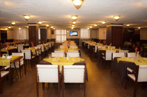 a dining room filled with tables and white chairs at Hotel 6 De Diciembre in Quito