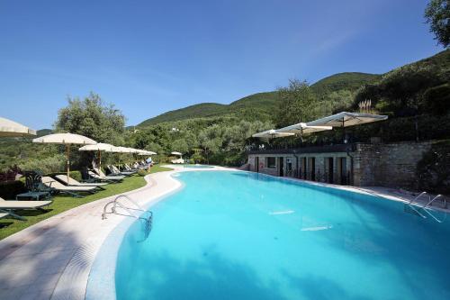 a large blue swimming pool with chairs and umbrellas at Appartamenti Borgo in Gardone Riviera