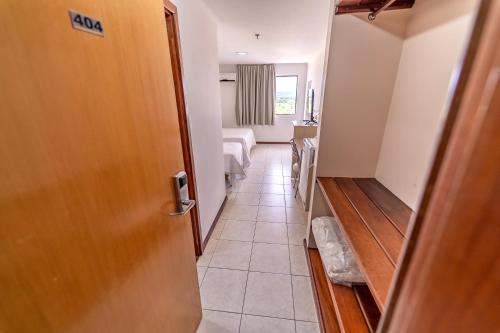 um corredor com uma porta e um quarto com uma cama em Rios Hotel em Rondonópolis
