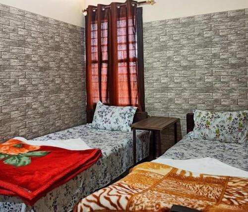 a room with two beds and a brick wall at D.D Lodge in Guwahati