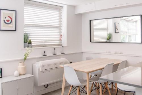 a white dining room with a table and chairs at Sutton House, Woodbridge in Woodbridge