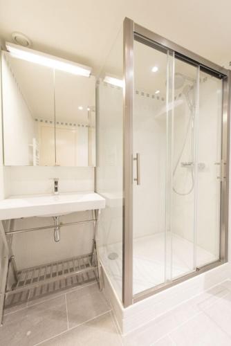 une salle de bain blanche avec une douche et un lavabo dans l'établissement Up & Down, à Paris