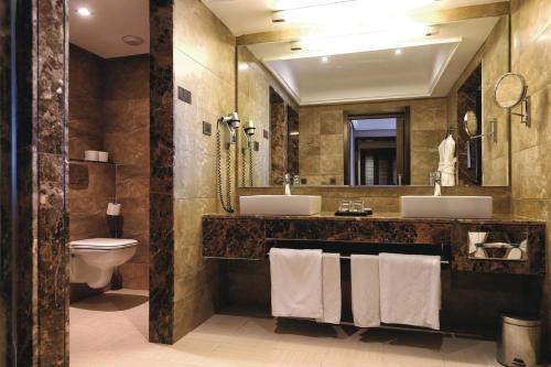 a bathroom with two sinks and a toilet and a mirror at Hotel Riu Palace Tikida Agadir - All Inclusive in Agadir