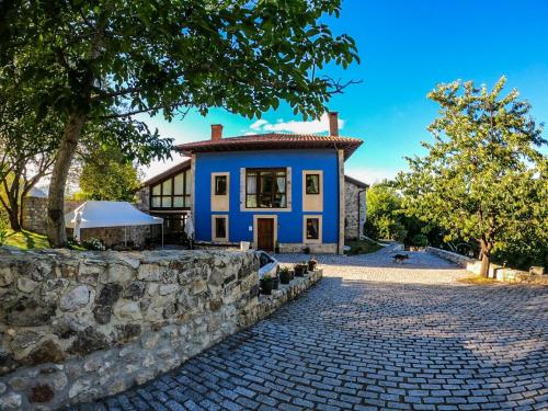 a blue house with a stone wall at Hotel Rural El Pandal in Ardisana