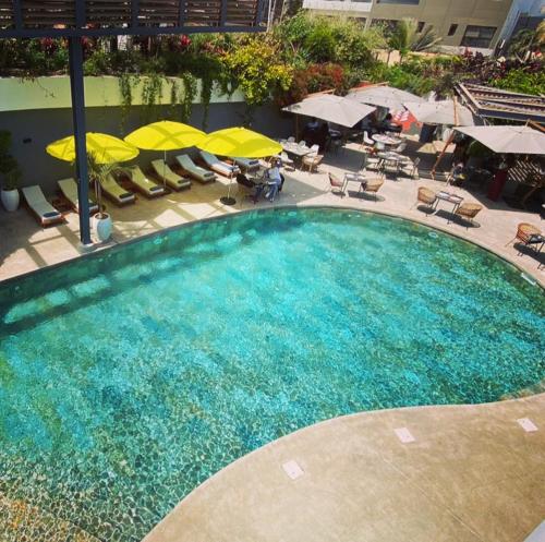 ein großer Pool mit gelben Sonnenschirmen und Stühlen in der Unterkunft BOMA LifeStyle Hotel in Dakar