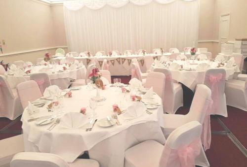 a room filled with white tables and chairs with white tablesearcher at Holiday Inn Ashford Central by IHG in Ashford