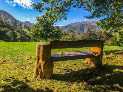 a wooden bench in a field with mountains in the background at Hotel Rural El Pandal in Ardisana