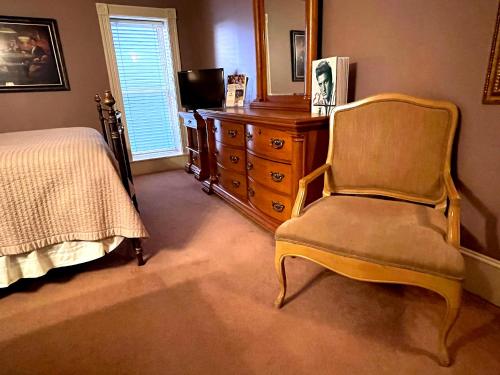 a bedroom with a bed and a chair and a dresser at Celebrity Boutique Hotel in Deadwood