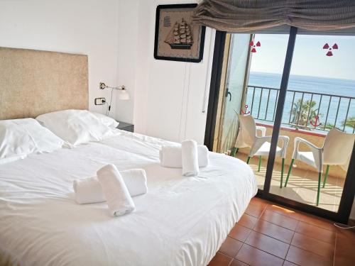1 dormitorio con cama blanca y vistas al océano en Apartaments Primera Linea Torre Valentina, en Sant Antoni de Calonge