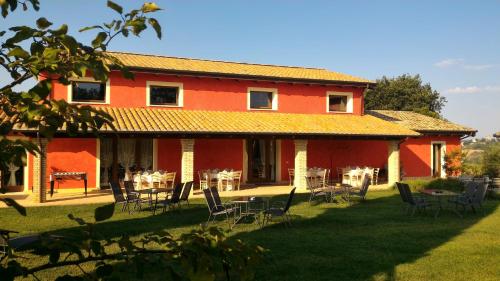 a red house with chairs and tables in the yard at Agriturismo La Capezzagna in Ripa Teatina