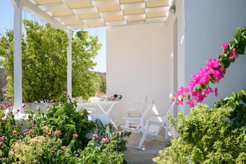 a patio with pink flowers and a white pergola at Mirabeli Apartments & Suites in Pollonia