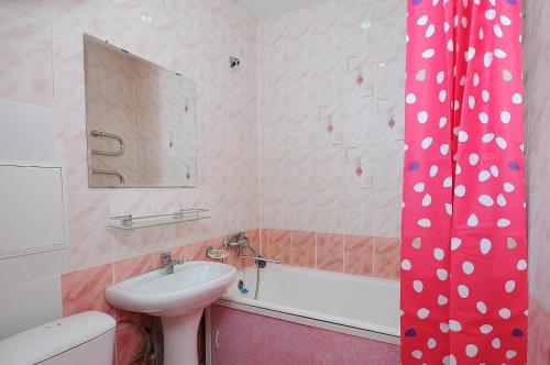 a bathroom with a sink and a toilet and a bath tub at Omsk Sutki Apartments at 4th Poselkovaya 44 in Omsk