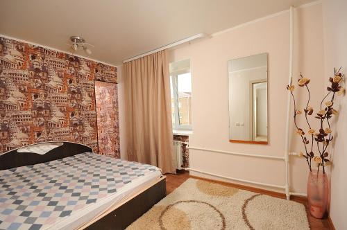 a bedroom with a bed and a wall with a mirror at Omsk Sutki Apartments at 4th Poselkovaya 44 in Omsk