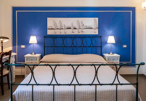 a blue bedroom with a bed and two lamps at B&B San Trifone in Adelfia