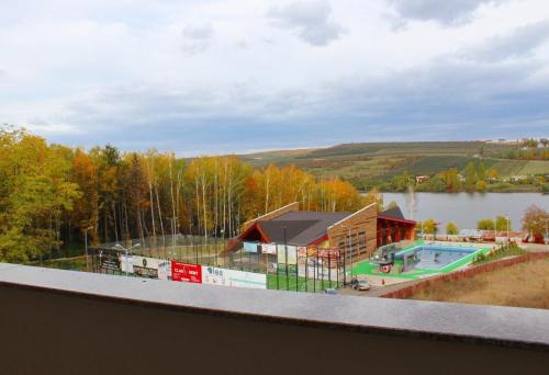 a building with a swimming pool next to a lake at Hostel Parc in Fălticeni