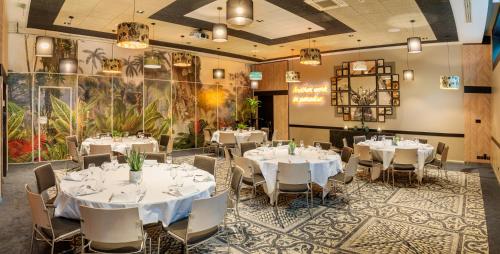une salle à manger avec des tables et des chaises blanches dans l'établissement Novotel Paris 14 Porte d'Orléans, à Paris