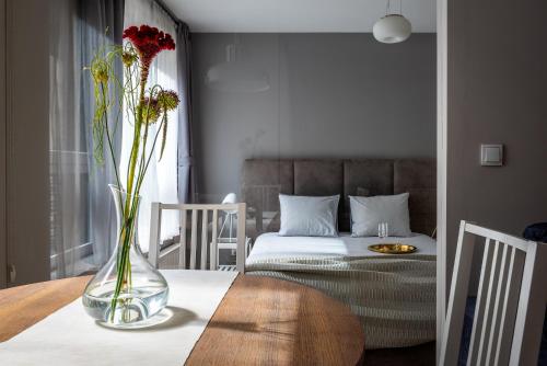 a vase with flowers on a table in a bedroom at apartamenty-wroc Golden House in Wrocław