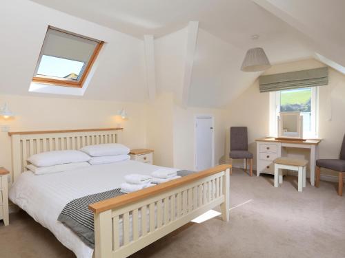 a bedroom with a bed and a desk and a window at 6 Chichester Court in Hope-Cove