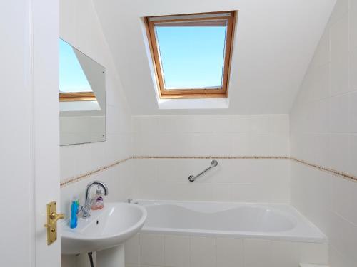 a white bathroom with a tub and a sink at 6 Chichester Court in Hope-Cove