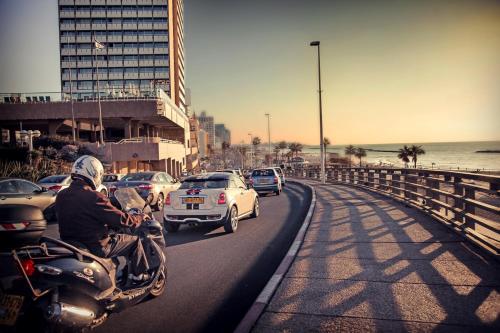 a man riding a motorcycle down a road with cars at Debrah Brown, a member of Brown Hotels in Tel Aviv