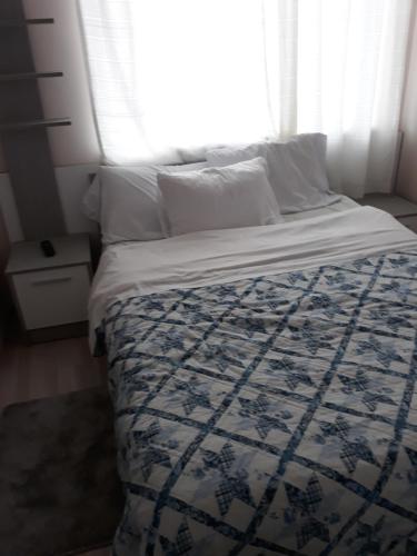 łóżko z niebiesko-białym kocem i oknem w obiekcie стаи за гости Севлиево studio for guests Sevlievo w mieście Sewliewo
