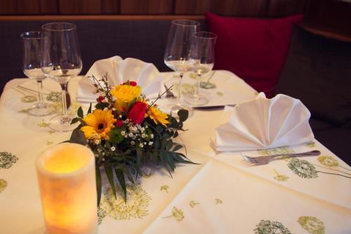 a table with a flower arrangement and wine glasses at Hotel Landgasthof Gemmer in Rettert