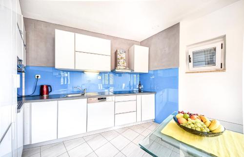una cocina con armarios blancos y un bol de fruta en una mesa en Apartman Andrej, en Povlja