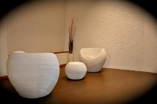 three white vases sitting on top of a wooden floor at Club Esse Cala Bitta in Baja Sardinia