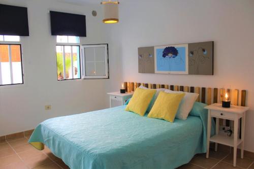 1 dormitorio con 1 cama con 2 mesas y 2 ventanas en Villa Delhi by Privilege Bay en La Oliva