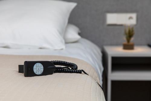 a black remote control on the edge of a bed at SPA Nida in Nida