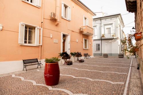 a courtyard with benches and a red pot on the ground at Casa Isabella B&B in Rocca San Giovanni