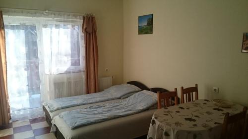 1 dormitorio con 2 camas, mesa y ventana en Margaréta Apartmanház, en Balatonlelle