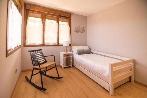a bedroom with a bed and a chair and a window at AGROTURISMO ZUMINTXAZ in Mungia