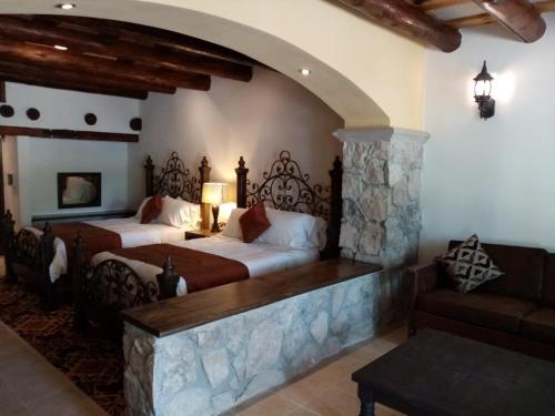 a bedroom with two beds and a stone wall at Hotel Quinta Mision in Creel