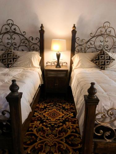 a bedroom with two beds and a lamp on a night stand at Hotel Quinta Mision in Creel