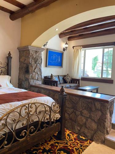 a bedroom with a bed and a stone wall at Hotel Quinta Mision in Creel