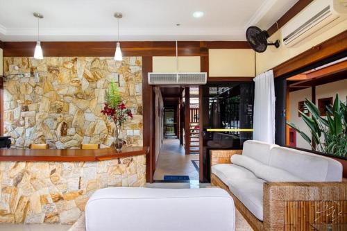 a living room with a stone wall at Suítes Trilha do Sol in Ubatuba