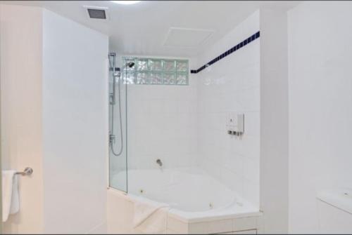 a white bathroom with a shower and a sink at Casablanca In Landmark Resort in Nelson Bay