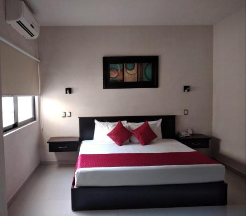 1 dormitorio con 1 cama grande con almohadas rojas en Hotel Madrid en Tuxtla Gutiérrez