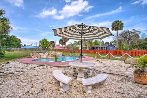 a table with an umbrella next to a pool at Cozy Melbourne Home with Deck and Pool 5 Mi to Beach! in Melbourne