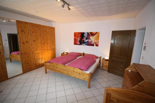 a bedroom with a bed with pink sheets and wooden cabinets at Komfort Ferienwohnung FEWO74-2 in Bremm
