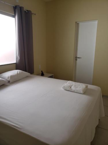 a bedroom with a white bed with a window at Pousada Litorânea in São Luís