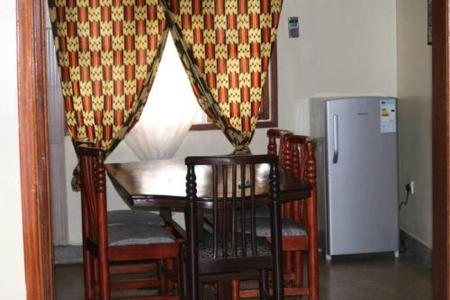 ein Esszimmer mit einem Tisch und Stühlen sowie einem Kühlschrank in der Unterkunft House 1759, near River Nile in Jinja