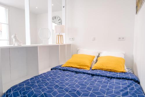 um quarto com uma cama azul e almofadas amarelas em AuPetitSaumur - LPC em Saumur