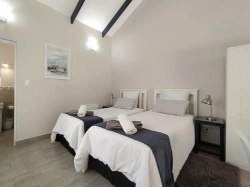 two beds in a room with white walls at Capricorn Studio Two - 150m to Solar Beach, Patio & Braai, Wifi, DSTV & Netflix in Plettenberg Bay