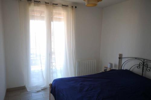 Un dormitorio con una cama azul y una ventana en Jolie petite Maison de Charme dans quartier boisé, en Vallauris