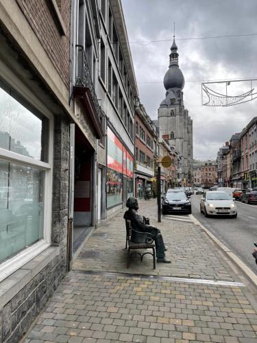 a person sitting on a bench on a street at Gîtes Sax 1 in Dinant