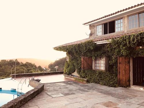 an ivycovered house with a swimming pool in front of it at Casa Fenteiras in Cangas de Morrazo