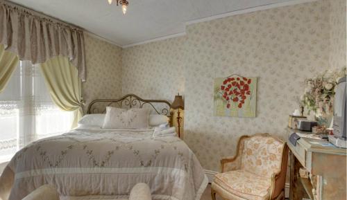 a bedroom with a bed and a chair and a window at Garden House Bed and Breakfast in Hannibal